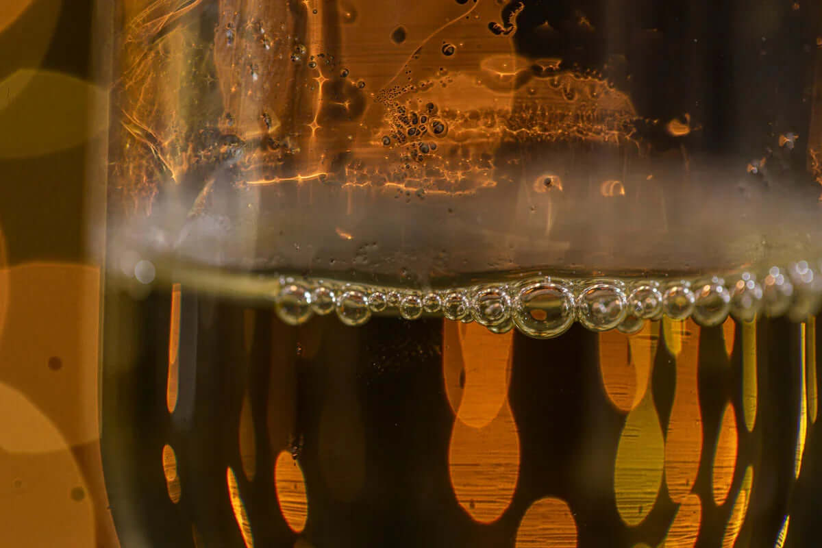 Close-up of sparkling champagne bubbles in a glass with golden reflections