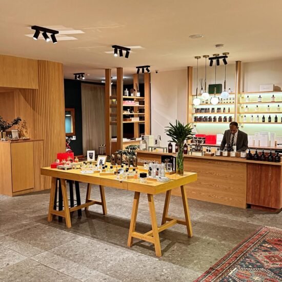 Modern boutique interior with wooden display table featuring perfumes and cosmetics.