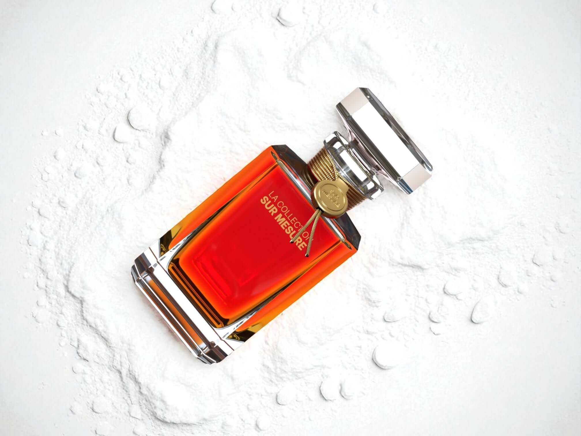 Elegant amber-colored perfume bottle with gold accents on white textured background.